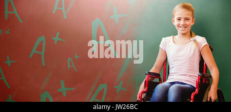 Girl sitting in wheelchair in school corridor against green chalkboard Stock Photo