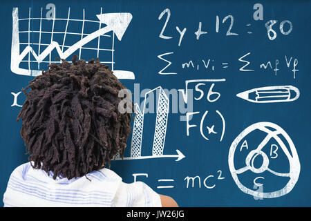 Rear view of boy with dreadlocks against blackboard with copy space on wooden board Stock Photo