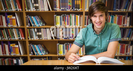 Student sitting in library reading  against various books on shelf Stock Photo