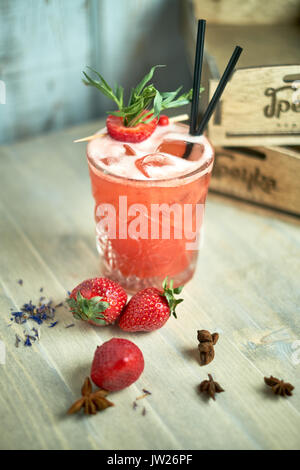 Strawberry lemonade with lime and ice in mason jar on a wooden table jpg