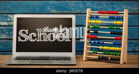 Back to school text against white background against laptop by abacus on table Stock Photo