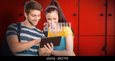 Happy students using tablet pc against close-up of orange lockers Stock Photo