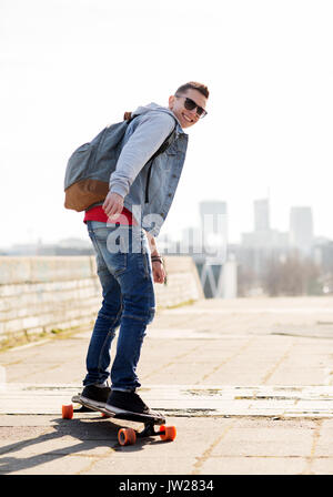 happy young man or teenage boy riding on longboard Stock Photo