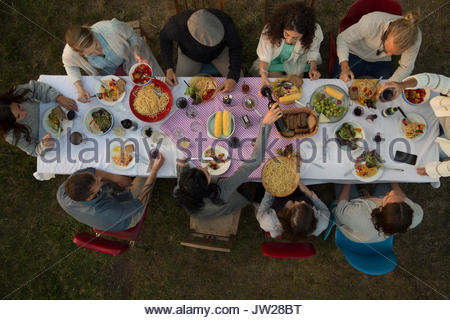 Overhead view friends eating and drinking at garden party dinner
