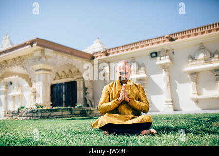 Handsom Indian Man Greeting Namaste, in Gold Kurta at the Temple Stock Photo