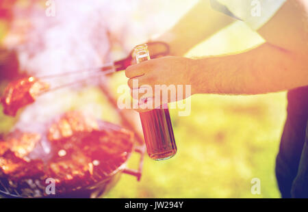 man cooking meat on barbecue grill at summer party Stock Photo