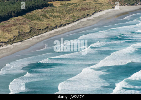 Spinning waves breaking at the flat sand beach, Allans Beach, Dunedin, Otago Peninsula, South Island, New Zealand Stock Photo