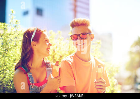 happy teenage couple eating hot dogs in city Stock Photo