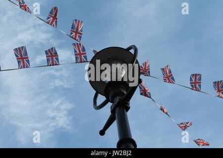 Patriotic flag bunting blowing in the breeze on a streetlamp against blue sky in Newton Abbot Devon.. Stock Photo