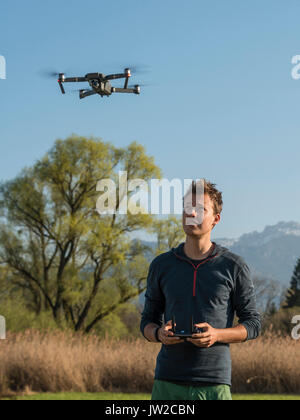 Young man controlling flying quadrocopter, remote controlled drone with camera, DJI Mavic Stock Photo
