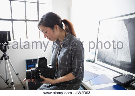 Female photographer adjusting digital camera lens in art studio