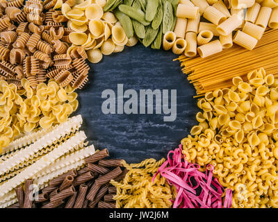 Photo of twelve different pasta types arranged on a slate surface as a frame. Stock Photo