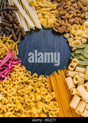 Photo of twelve different pasta types arranged on a slate surface as a frame. Stock Photo