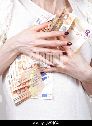 Woman with skinny hands holding Euro banknotes pile on her chest Stock Photo