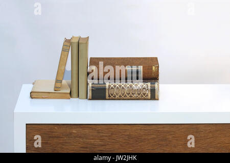 Old vintage hard cover books on white wooden shelf Stock Photo