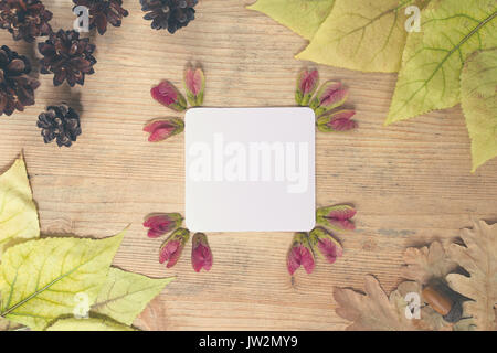 Autumn background - frame of multi-colored autumn leaves with a sheet of paper for text on a wooden background Stock Photo