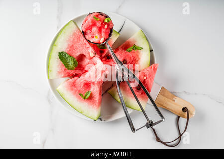 Summer fruit desserts, frozen cocktails. Ice cream granite from watermelon with mint, one scoop in spoon for ice cream, on plate with slices of waterm Stock Photo