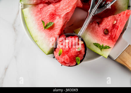 Summer fruit desserts, frozen cocktails. Ice cream granite from watermelon with mint, one scoop in spoon for ice cream, on plate with slices of waterm Stock Photo