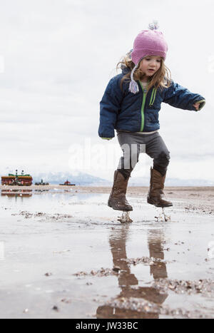 Little girl (4-5) jumping in puddle Stock Photo