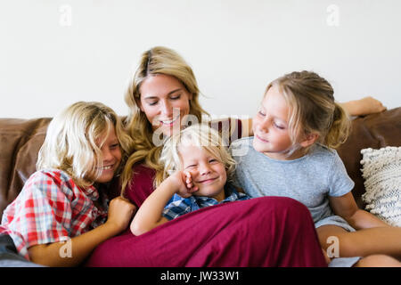 Mother and children (4-5, 6-7, 8-9) resting in living room Stock Photo