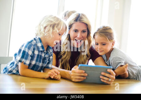 Mother with kids (4-5, 6-7, 8-9) using digital tablet Stock Photo