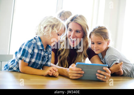 Mother with kids (4-5, 6-7, 8-9) using digital tablet Stock Photo