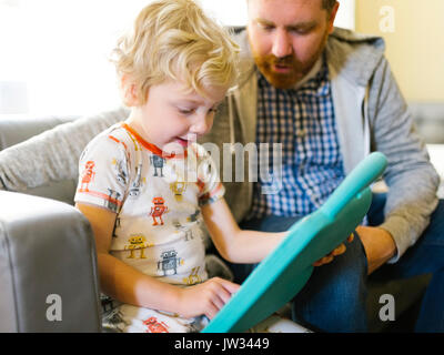 Father and son (4-5) playing with electronic toy Stock Photo