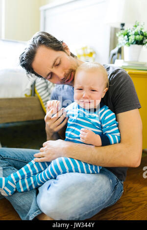 Father embracing sad son (12-17 months) Stock Photo