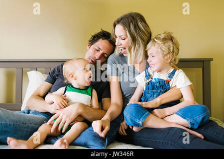 Parents playing with sons (12-17 months, 4-5) on bed Stock Photo