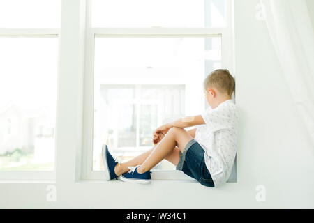 Boy (7-8) looking through window Stock Photo