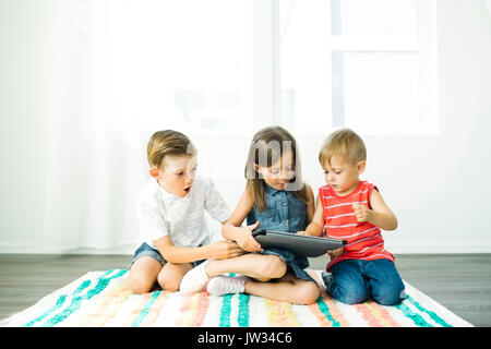 Siblings (2-3, 6-7) using digital tablet at home Stock Photo