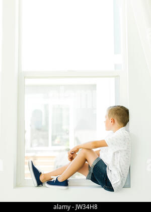Boy (6-7) looking through window Stock Photo