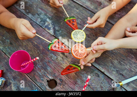 Hands of children with sweets on a wooden  background. Stock Photo