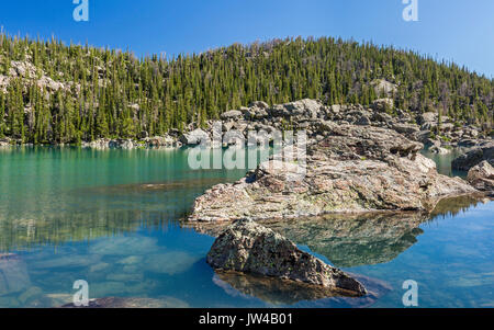 Blue sky reflects in the vivid green waters of Lake Haiyaha in Rocky Mountain National Park, Colorado Stock Photo