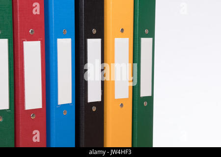 Close up of a row of multicoloured office document folders with blank labels and plain white background with copy space. Stock Photo