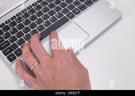 Close up of a mans hand zooming on laptop keyboard mouse tracking pad with white copy space. Stock Photo