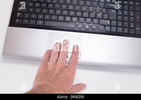 Close up of a mans hand with wedding ring using a tracking pad on a computer laptop with white background and copy space. Stock Photo
