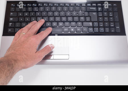 Close up of a mans hand pressing the space bar button on a computer laptop with white background and copy space. Stock Photo