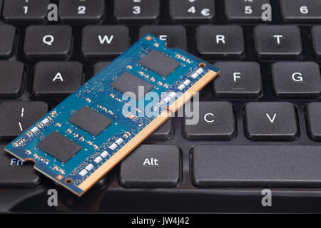 Close up of a blue computer chip circuit board on a black keyboard. Stock Photo