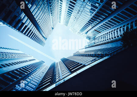 Airplane contrail against clear blue sky with abstract low angle view of common modern office skyscrapers. Stock Photo