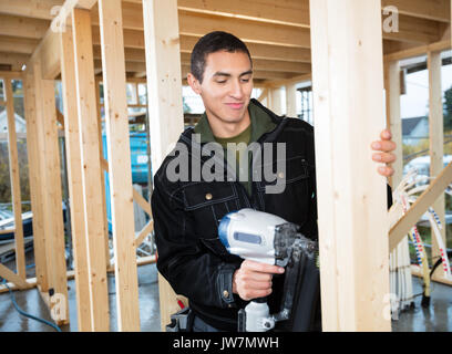 Young male carpenter using airgun Stock Photo