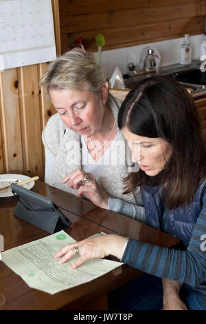 Two women researching family tree on kindle Stock Photo