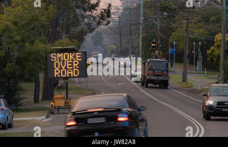 A variable message sign warning motorists of smoke over the road and a fire engine during a hazard reduction burn in Sydney Stock Photo