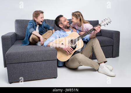 happy family playing on guitar and singing, spending time together while sitting on sofa Stock Photo