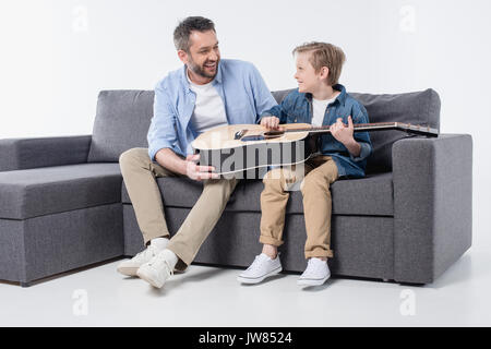 smiling father teaching his adorable son to play on guitar Stock Photo