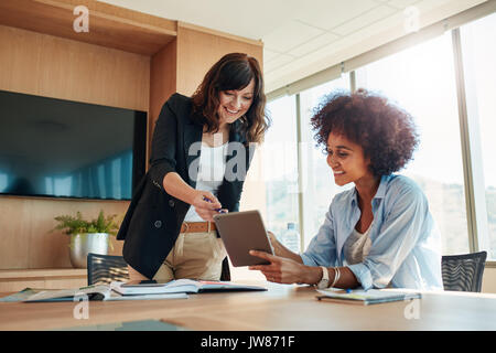 Shot of business professionals having a meeting in office using digital tablet. Business partners using touchscreen computer for project discussion. Stock Photo