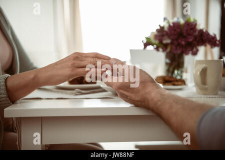 cropped view of senior couple holding hands during breakfast Stock Photo