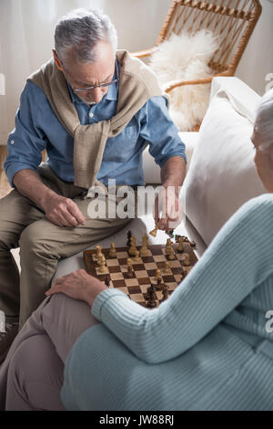 Pensive woman sitting at table in living room while thinking about next  chess move. Stock Photo by DC_Studio