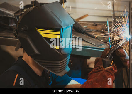 Male in face mask welds with argon-arc welding Stock Photo