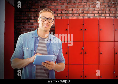 Student using tablet against orange lockers against brick wall Stock Photo